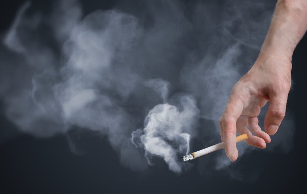 Smoker is holding smoking cigarette