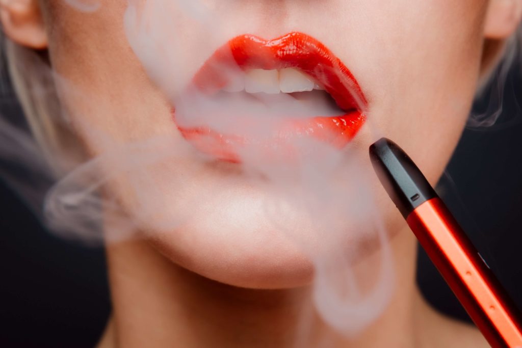A close-up image of a woman's lips and a vape